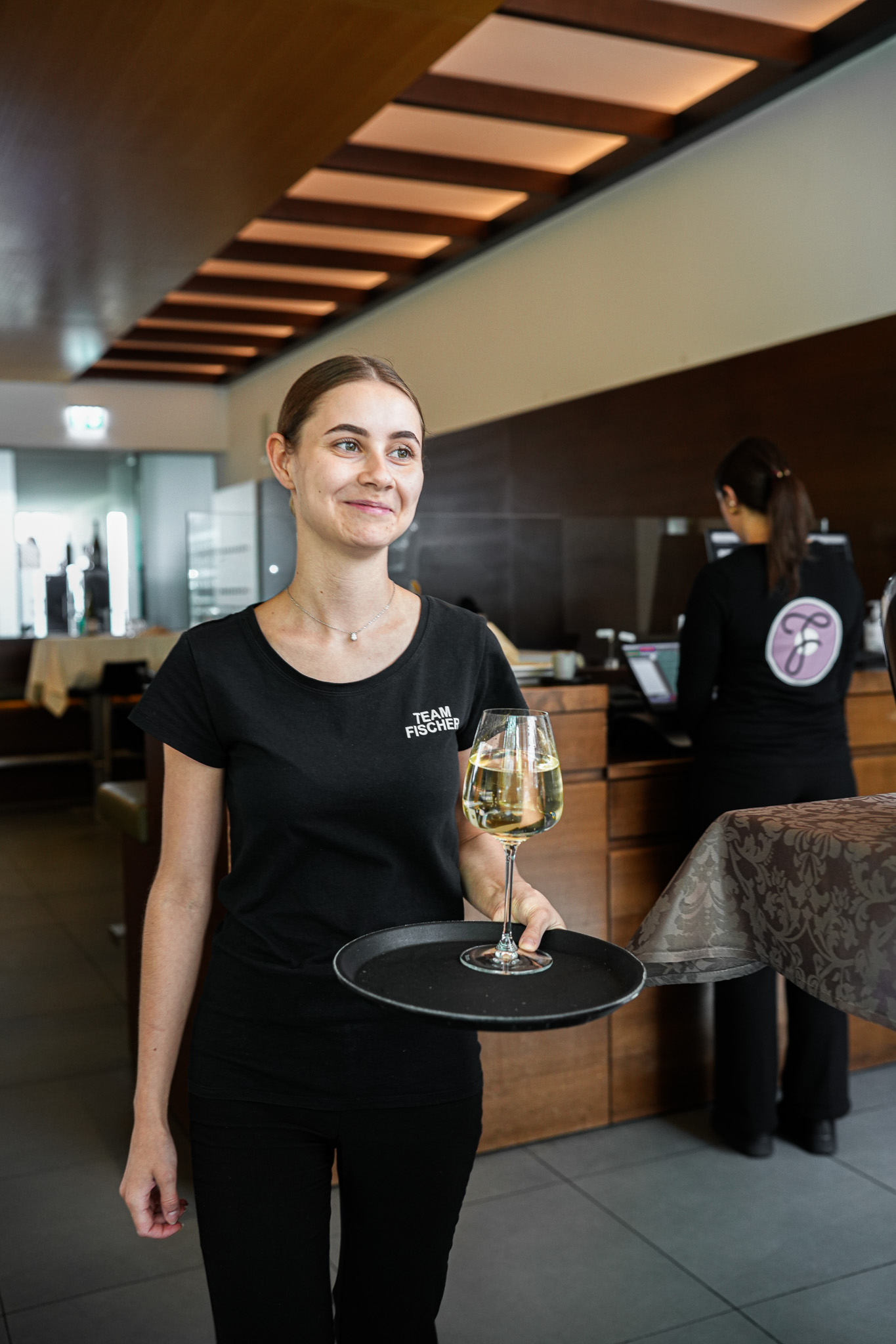 Servicekraft vom Team Fischer mit Weinglas
